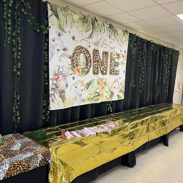 Tables with gold, black coverings and "Wild One' banner hanging behind
