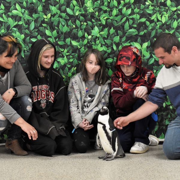 smiling family poses with penguin