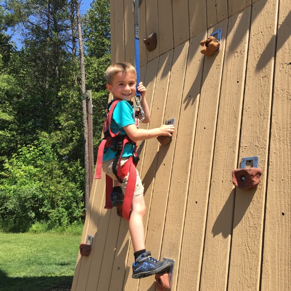 smiling boy pauses for photo on climbing wall