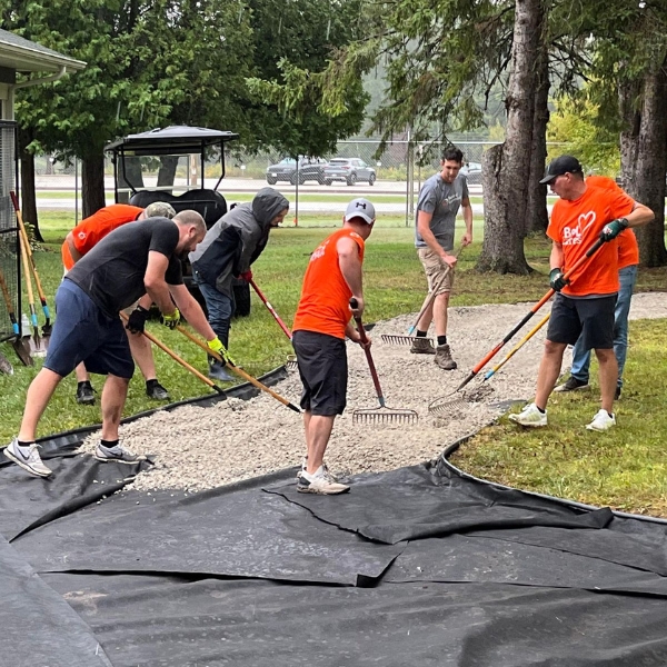 Volunteers use rakes to spread rock on new pathway