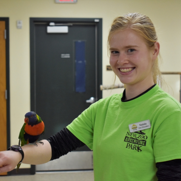 Smiling staff member holds lorikeet on her arm