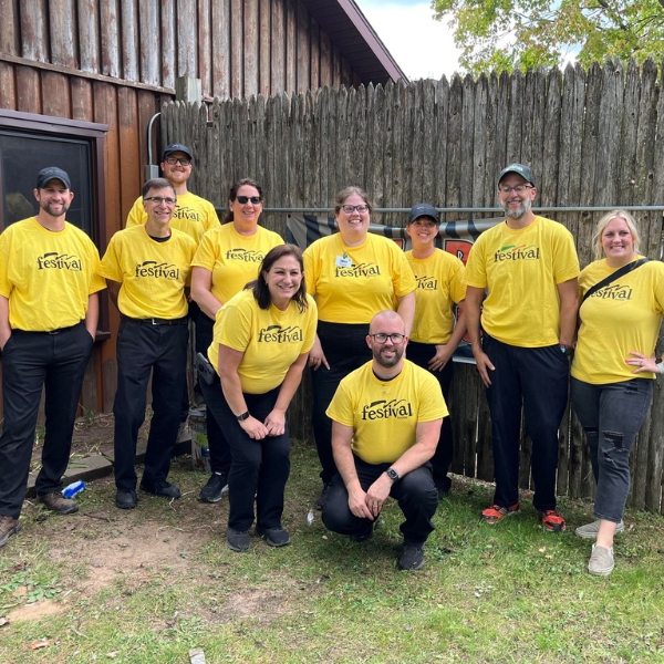 Group of smiling volunteers stand in front of fence