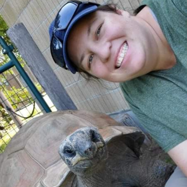 Smiling Zookeeper kneels by tortoise
