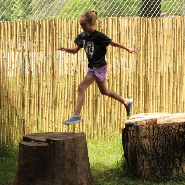 Camper jumps between logs in Discovery Zone