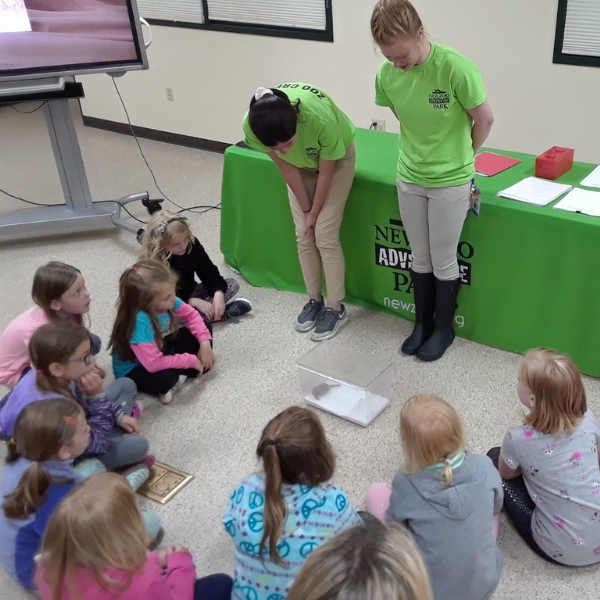 Scouts sit in circle while learning from zoo teachers