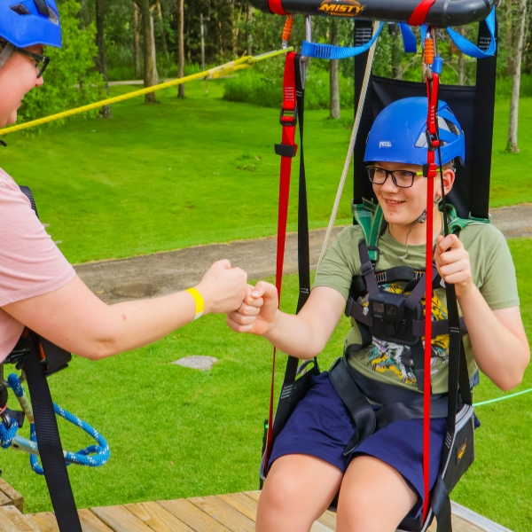 Smiling child sits in adaptable zip harness