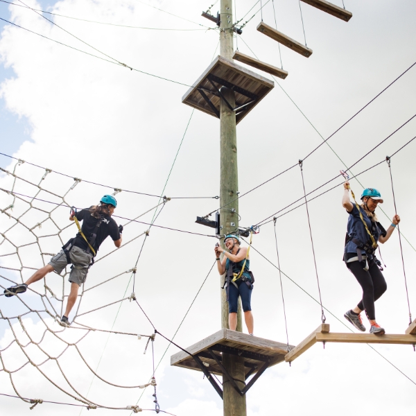 Three adults climbing the Ropes Course