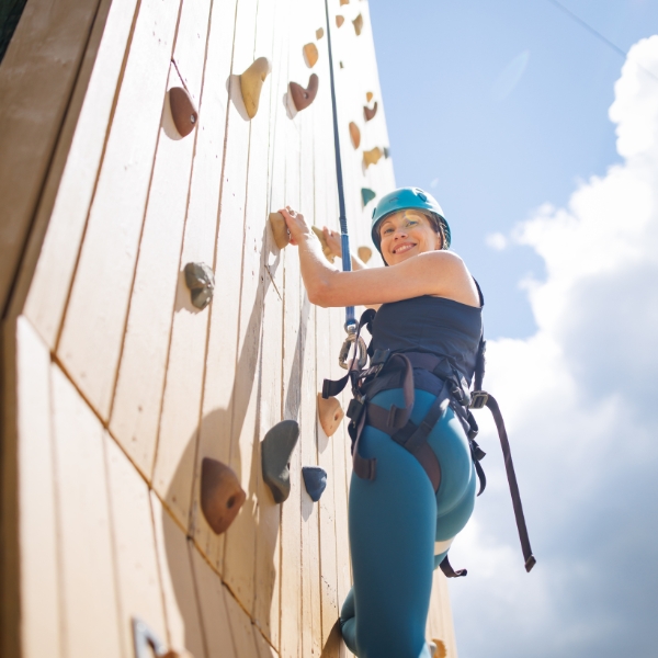 Woman in helmet and harness smiles while looking down from Climbing Tower